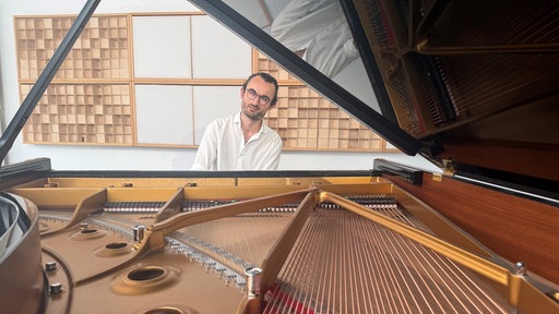 Marc Vogler sitzt am geöffneten Flügel.