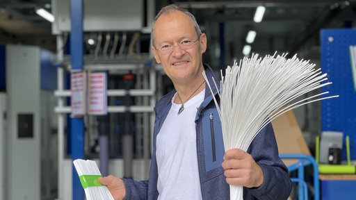 Klaus Vossenkaul hält zwei Bündel der Membranen in den Händen.