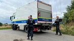 Polizeibeamten stehen neben einem Polizeiwagen in der Nähe des Braunkohlekraftwerks Weisweiler.