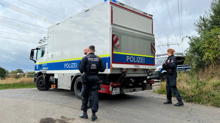 Polizeibeamten stehen neben einem Polizeiwagen in der Nähe des Braunkohlekraftwerks Weisweiler.