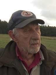 Älterer Mann, Karl-Heinz Jansen, im Interview auf einem Feld, hinter ihm Wald