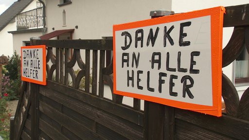 Ein Gartenzaun an dem Zwei Schilder angebracht sind. Darauf steht "Danke an alle Helfer".