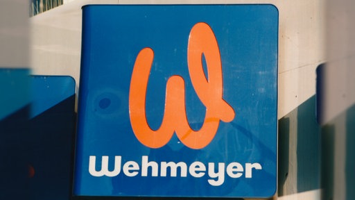 Ein Schild von der Firma Wehmeyer, mit orangem 'W' auf blauem Hintergrund