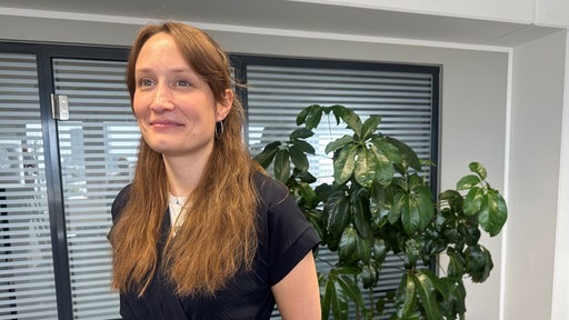 Lächelnde Frau mit langen braunen Haaren.