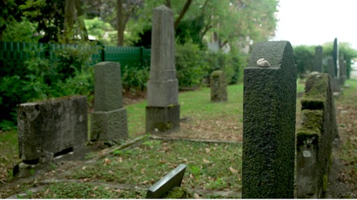 Alte, zum Teil mit Moos bewachsene Grabsteine auf einem Friedhof