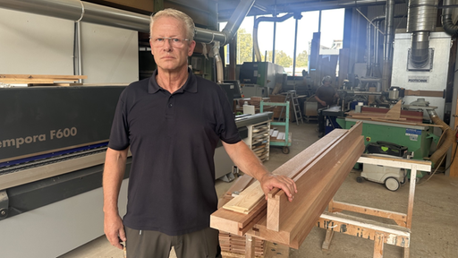 Ein Mann mit Brille steht in seiner Werkstatt