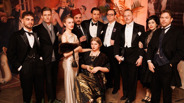 Mehrere Leute stehen für ein Foto in eleganten Posen und Abendkleidung