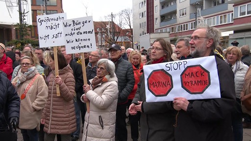 Frust bei Monheimer Brügerinnen und Bürgern: Sie stehen mit Plakaten auf einer Kundgebung und machen ihrem Unmut Luft.