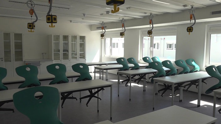 Ein Klassenraum mit Stuhlreihen, mehreren Schränken und Steckdosen von der Decke