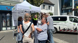 Menschen stehen vor einem "Stadt Langenfeld Referat Ordnung" Stand in der Stadt