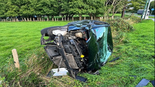 Auto in Seitenlage auf einer grünen Wiese ist beschädigt