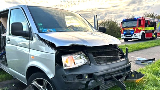 Verunfallter Transporter mit Feuerwerfahrzeug im Hintergrund
