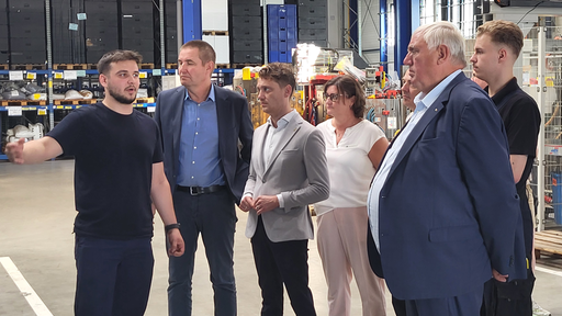 Karl-Josef Laumann im Gespräch mit Mitarbeitern in einer Fabrikhalle 