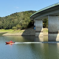 Rotes Boot auf dem Wasser vor einer Betonbrücke 