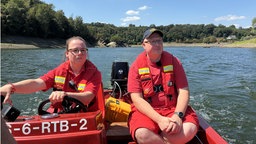 Ein Mann und eine Frau sitzen mit Schwimmwesten in einem Boot. 