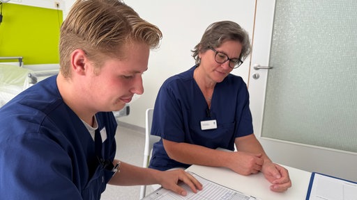 Zwei Pflegeazubis lesen die Patientenakte