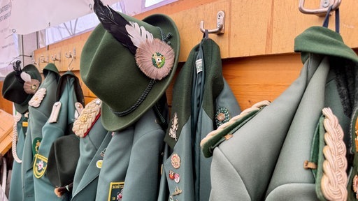 Grüne Uniformen hängen an Kleiderhacken.