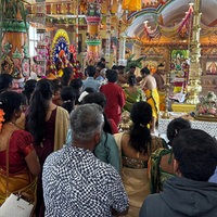 Menschen stehen vor einem bunt geschmückten Altar in der Tempelmitte.