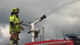 Ein Feuerwehrmann bedient einen Wasserwerfer gegen Waldbrand