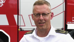 Ein Feuerwehrmann steht vor einem Feuerwehrauto
