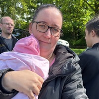 Eine Mutter mit einem Baby auf dem Arm guckt in die Kamera