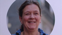 Eine Frau schaut in die Kamera und lacht.