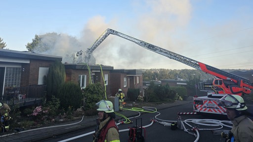 Feuerwehrleute im Einsatz vor einem Reihenhaus