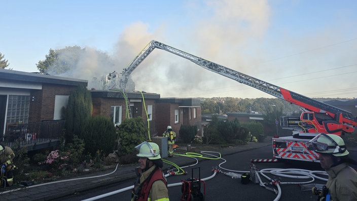 Feuerwehrleute im Einsatz vor einem Reihenhaus