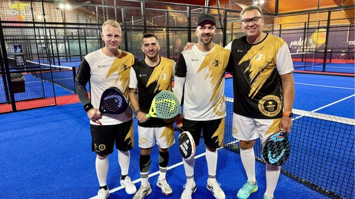 Vier Männer in Trikots stehen in einer Padel-Halle.