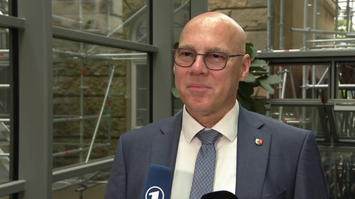 Wuppertals Oberstaatsanwalt Wolf-Tilman Baumert steht auf dem Gerichtsflur, vor ihm sind Mikrofone