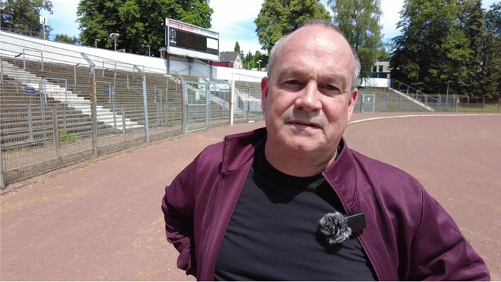 Mann mit roter Jacke steht im Stadion