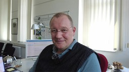 Mann mit Brille sitzt im Büro vor Computer