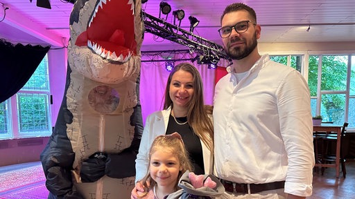 Die Familie steht gemeinsam neben einem Krokodil-Maskottchen 