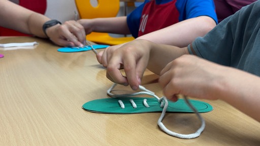 eine Kinderhand bindet eine Schleife