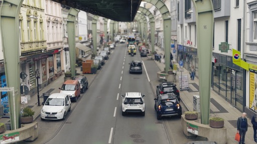 Blick auf die Straßen Wuppertals. Unter dem Schwebahngerüst verläuft die Straße mit Autos.