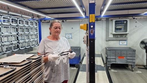 Eine Frau mit Handschuhen schaut prüfend auf ein Chromteil.
