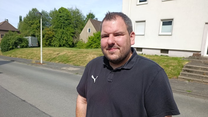 Mann mit kurzen Haaren, einem Drei-Tage-Bart und einem schwarzen Puma-Polo-Shirt.