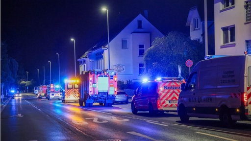 In Solingen stehen Notarzt- und Rettungswägen in der Nacht auf einer bewohnten Straße, entlang der einige Straßenlaternen stehen