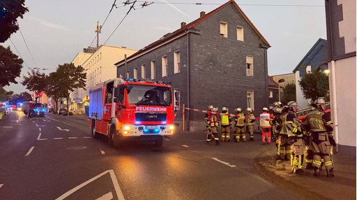 Ein Feuerwehrfahrzeug steht mit ausgefahrener Drehleiter vor einem Wohnhaus