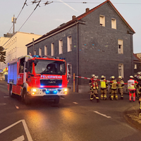 Ein Feuerwehrfahrzeug steht mit ausgefahrener Drehleiter vor einem Wohnhaus