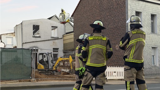 Feuerwehrleute vor einem kaputten Gebäude