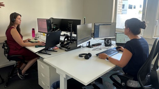 Arbeitnehmer sitzen im Büro an Schreibtischen gegenüber