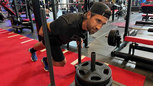 Sportler schiebt Schlitten in Fitnessstudio
