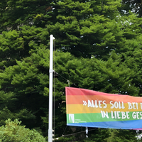Eine Regenbogenflagge vor der Lutherkirche in Solingen auf der steht "Alles soll bei euch in Liebe geschehen."