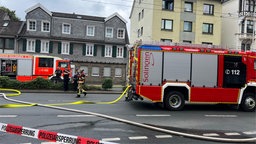 Einsatzwagen der Feuerwehr und Feuerwehrleute bei der Arbeit