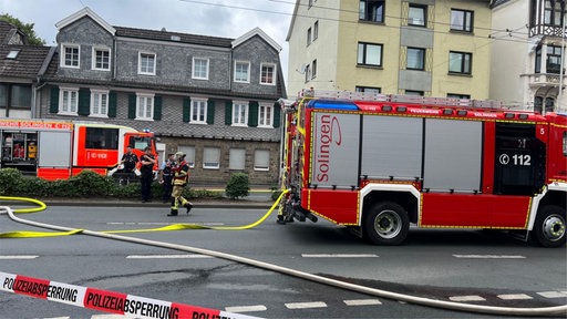 Einsatzwagen der Feuerwehr und Feuerwehrleute bei der Arbeit