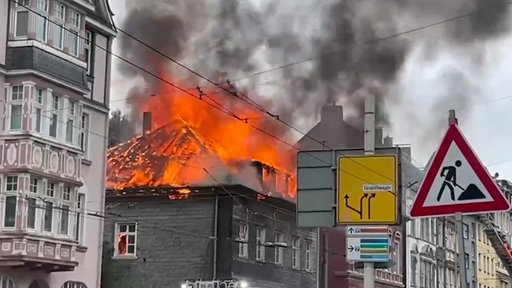 Brennender Dachstuhl eines Hauses in der Innenstadt aus dem Rauch und Feuer emporsteigt 