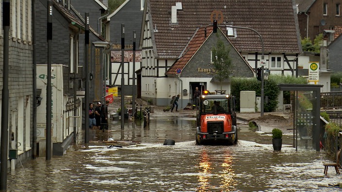 Überflutete Strasse in Soingen Unterbrug. Radlader fährt durch Wasser