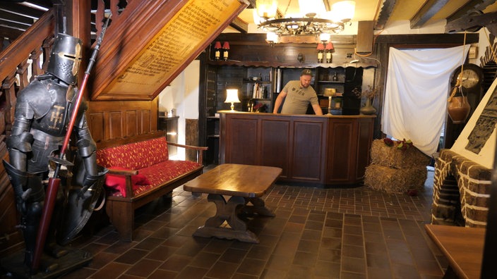 Mann steht hinter einer Rezeption in historischem dunklem Hotelambiente