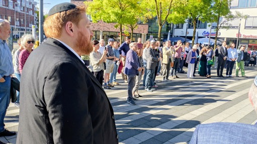 Menschen mit Kippa stehen auf einem Platz.